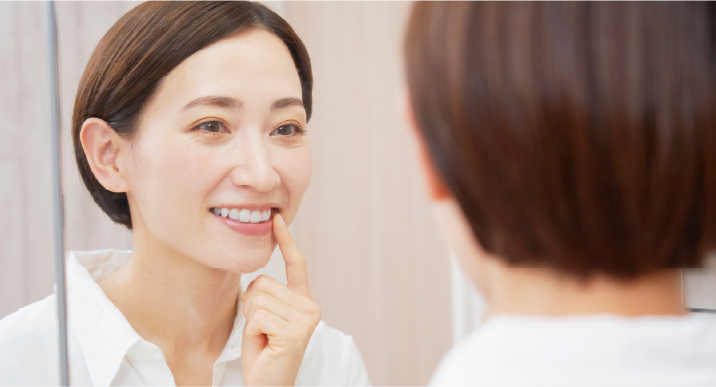 鏡で歯を見る女性