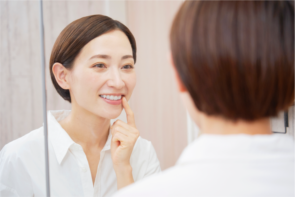 鏡の前で歯をチェックする女性